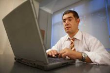 A man in white shirt and tie using laptop.